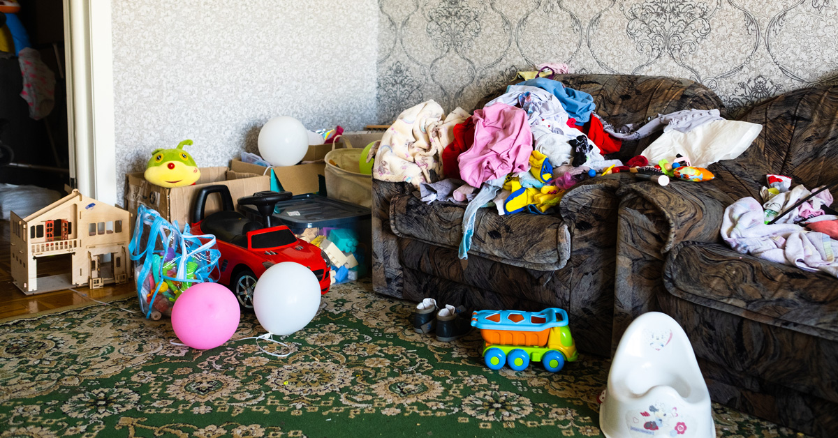 A living room that's cluttered with toys, clothes, and other items.